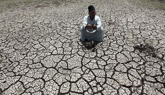 An Egyptian farmer squats down on cracked soil to show the dryness of the land due to drought in a farm formerly irrigated by the river Nile, in Al-Dakahlya
