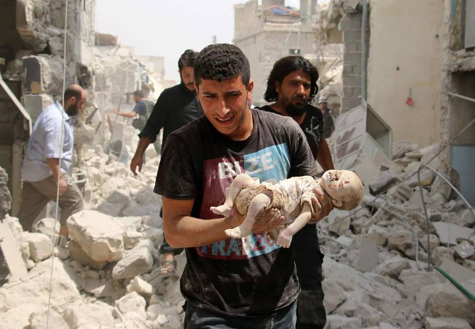 A man carries a child who was killed by Assad-Russian airstrikes on Aleppo